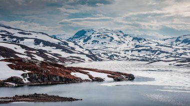 Landscape of Hardangervidda with mountains, snow, ice and lake in Norway during spring