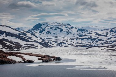 Landscape of Hardangervidda with mountains, snow, ice and lake in Norway during spring