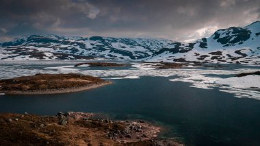 Snowy landscape of Hardangervidda national park with mountains and icy lakes in Norway, from above