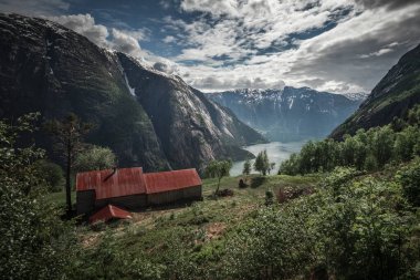 Old shed on top of Eidfjord in Norway, red rooftop and green vegeation