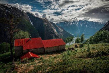 Old shed on top of Eidfjord in Norway, red rooftop and green vegeation
