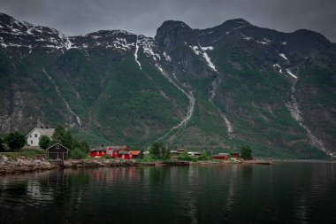 Houses at the waterfront of small town of Eidfjord in Norway, surrounded by mountains of the fjord