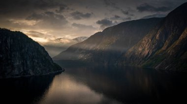 Sunset in the fjord and mountain landscape Eidfjord in Norway from above, sun rays falling through clouds