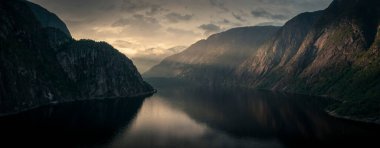 Sunset in the fjord and mountain landscape Eidfjord in Norway from above, sun rays falling through clouds