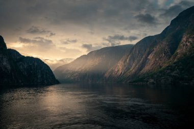 Sunset in the fjord and mountain landscape Eidfjord in Norway from above, sun rays falling through clouds