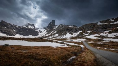 Mountain landscape of Litlefjellet Isfjorden with peak, road and snow in Norway Trollveggen, dramatic sky with dark clouds