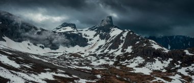 Mountain landscape of Litlefjellet Isfjorden with peak, road and snow in Norway Trollveggen, dramatic sky with dark clouds, from above