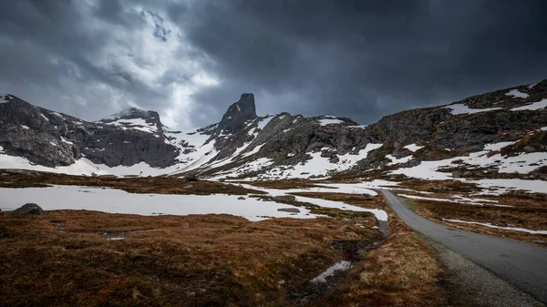 Mountain landscape of Litlefjellet Isfjorden with peak, road and snow in Norway Trollveggen, dramatic sky with dark clouds