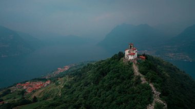 Chapel Santuario della Madonna della Ceriola yukarıdan Iseo Gölü 'nde Monte Isola Dağı' nın zirvesinde, arka planda dağlar ve göl, İtalya 'da baş döndürücü bulutlar. Haziran 2023
