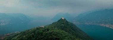 Chapel Santuario della Madonna della Ceriola yukarıdan Iseo Gölü 'nde Monte Isola Dağı' nın zirvesinde, arka planda dağlar ve göl, İtalya 'da baş döndürücü bulutlar. Haziran 2023