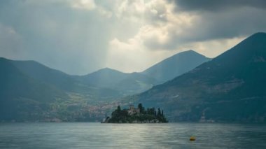 Isola di Loreto Gölü 'ndeki kalenin üzerindeki güneş ışınlarının zamanlaması, arka plandaki dağlar, gökyüzündeki bulutlar, İtalya