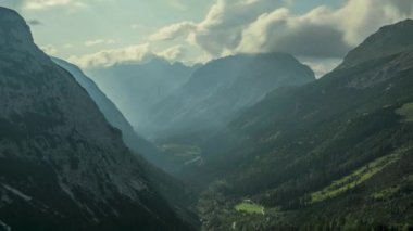 Yazın güneşli mavi gökyüzü gününde Karwendel dağlarındaki vadide hareket eden bulutların ve güneş ışınlarının zamanlaması yukarıdan gelen güneş ışınları gökyüzündeki beyaz bulutları delip geçiyor, Tyrol Avusturya