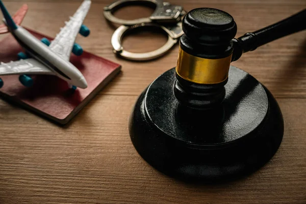 Concept of aviation law,international law, immigration law and citizenship rights. Gavel, passport, hand cuff and toy plane on a wooden background.