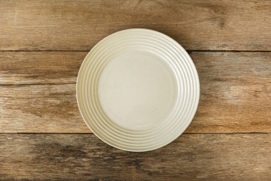 Top view of empty white cream plate on a wooden background. Flat lay, copy space.