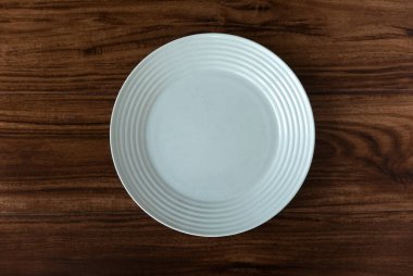 Top view of empty white cream plate on a wooden background. Flat lay, copy space.