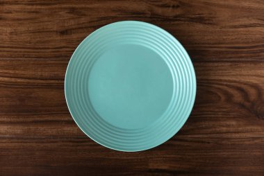 Top view of empty green plate on a wooden background. Flat lay, copy space.
