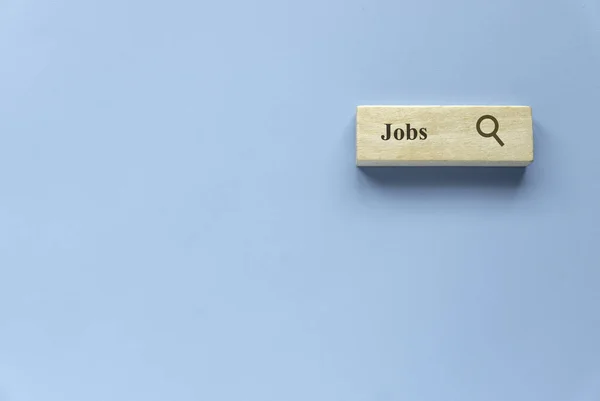 Searching for a new job, employment, a career, a job opportunity, or a work position concept. Wooden search bar isolated on a blue background with copy space.