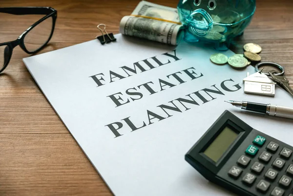 Aile mirası planlaması. Emlak yatırımı ve ev ipoteği finansal emlak konsepti. Belge, para, hesap makinesi, gözlük ve anahtar ahşap masada..