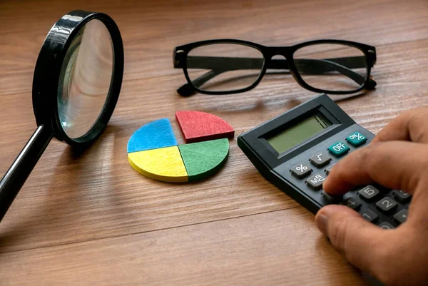 Quarterly report concept. Company financial report. Business charts. Colorful quarter wooden pie chart pieces with calculator.