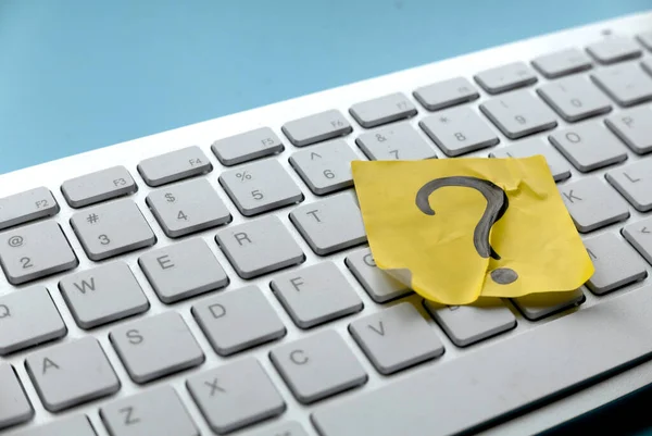 Q&A or questions and answers concept. Yellow sticker with handwritten question symbol over computer keyboard.
