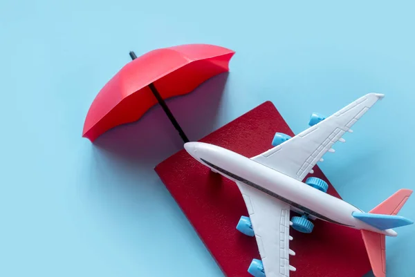 旅行保険の概念 安全旅行 航空便の遅延 キャンセル スーツケースの損傷や損失 事故や医療費のカバー 飛行機とパスポートの赤い傘カバー — ストック写真