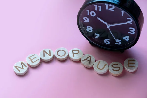 Alfabe, saat üzerinde bir kelime menopozu oluşturur. Kadınlar için sağlık ve tıbbi konsept. Pembe arkaplan