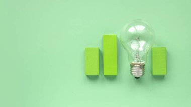 Yeşil arkaplanda ampulün üst görüntüsü. Enerji tasarrufu kavramı, yenilenebilir enerji ve çevre dostu. Boşluğu kopyala.