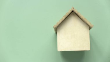 Çevre dostu ev kavramı. Eko ev ve gayrimenkul. Ahşap ev modeli, yeşil arka planda. Boşluğu kopyala.