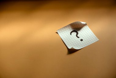 Sorular ve cevap konsepti. Kağıda yazılmış soru işareti. Kahverengi gölge arkaplanı.