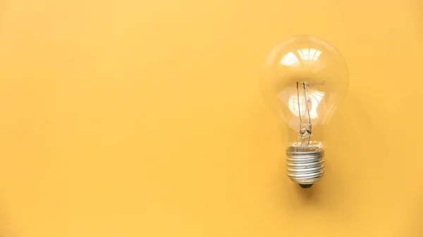Creative thinking idea, innovation and inspiration concept. Bulb on yellow background. Copy space.