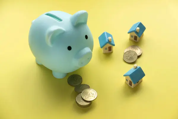 Concept of saving for house and property.Miniature house with piggy bank.