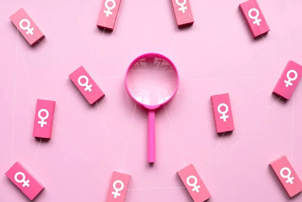 Questions and answers about women concept. Women symbol over a wooden rectangular with pink magnifying glass on pink background.