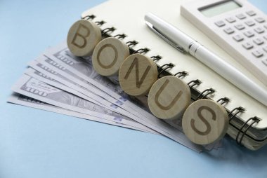 Bonus konsepti. Hesap makinesi, kalem ve defter ile dolar parası.