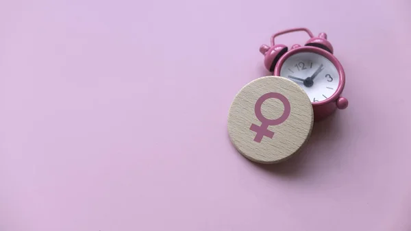 閉口概念 時計の上に女性のシンボル 女性のための医療と医療 コピースペース付きピンクの背景 ストックフォト