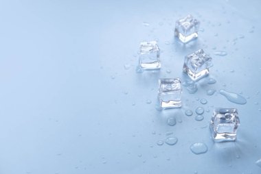 Soğuk ve ferahlatıcı kavramı. Mavi zemin üzerinde su damlaları olan buz küpleri.