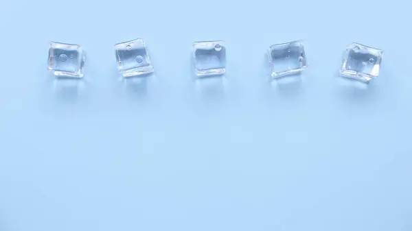 Concept of cold and refreshing. Ice cubes with water drops on a blue background.