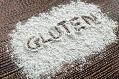 Masaya serpilmiş un tozu üzerine yazılmış glüten..