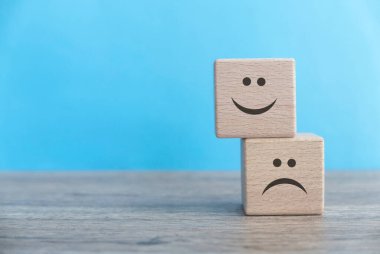 Yığılmış Duygular: Serene Blue Arkaplanına Karşı Ahşap Küpler ile Neşeli Bir Mutluluk ve Üzüntü Gösterisi