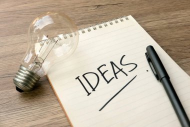 Ampul, Not Defteri ve Ahşap Masadaki Kalem ile Yaratıcı Fikirler