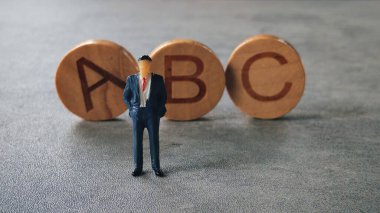 Takım Elbiseli Minyatür Şekil Alfabe Bloklarının yanında duruyor 