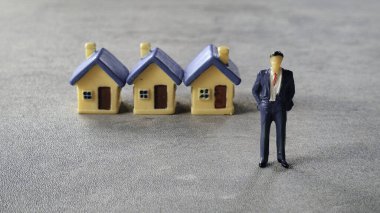 Minyatür bir evin önünde duran bir iş adamı..