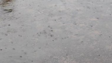 Yağmur damlaları ve sıçramalarla nemli beton yüzey, son yağmuru gösteriyor