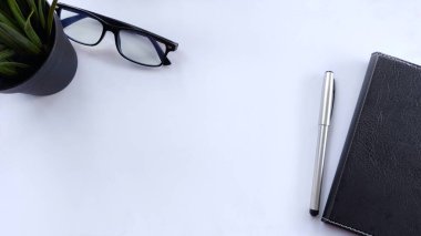 Minimalist düz çalışma alanı, bitki, gözlük, defter ve kalemle bembeyaz. İş, planlama, üretkenlik, zaman yönetimi, geniş kopya alanı ile günlük gündem için ideal.