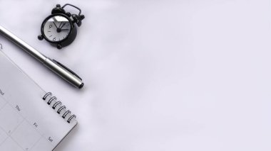 Beyaz üzerine kalem, takvim ve çalar saatin yer aldığı minimalist düz çalışma alanı. İş, planlama, üretkenlik, zaman yönetimi, geniş kopya alanı ile günlük gündem için ideal.