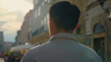 Tanımlanamayan erkek turistin arkadan görünüşü... yeni şehirler... açık havada esmer bir adam... şehir binalarına bakıyor... gezintiden zevk alan mutlu erkek gezginlerin manzarasını inceliyor.