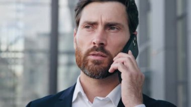 Kendine güvenen ciddi iş adamı portresi. Telefonlara cevap veriyor. İş görüşmeleri.