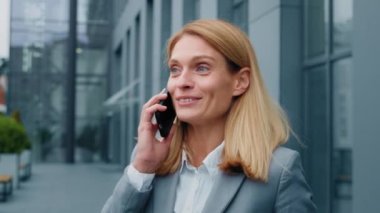 Mutlu, coşkulu, heyecanlı bir kadın dışarıda cep telefonuyla konuşuyor. Arkadaşlarıyla iyi bir deneyim paylaşıyor. Akıllı telefonlu neşeli iş kadını telefonda müşteriyle konuşuyor.