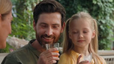 Kafkasyalı aile babası kadın ve kız çocuğu sakallı babayı annemle konuşurken yaklaş. Baba, anne ve küçük kız portakal suyu içiyorlar. Kamp yaparken vitaminlerin tadını çıkarıyorlar.
