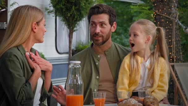 带着女儿的父母在面包车附近的户外露营时带着果汁和羊角面包野餐 — 图库视频影像
