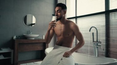 Çıplak, çıplak, çıplak, Latin, milenyum sakallı, banyo yapmadan önce banyoda duş jeli, krem losyon, kozmetik kokulu sabun kokan bir adam.